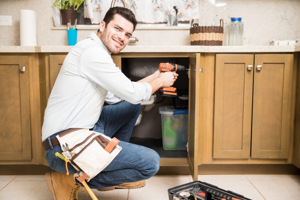 A man fixing the cabinets in his kitchen.